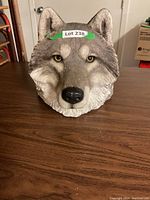 Front view of realistic wolf head wall sculpture placed on table.