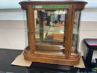 Front view of wood and curved glass curio cabinet with shelves and light inside