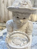 Close-up of the girl's face and basket showing detailed features and surface wear.