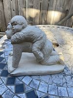 White Austin sculpture showing two children, one kneeling and the other resting on their back from side angle.