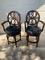 Two swivel counter bar stools side by side in front of a garage door, showing full front view and overall condition.