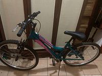 Full side view of the Huffy Tundra 26 women's mountain bike showing matte teal frame, tires, seat, and handlebars