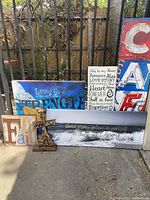 Five canvas artworks and a wooden cross arranged against a fence outside. Photos show different angles and the condition of the items.