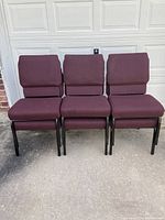 Front view of three burgundy upholstered chairs in a set, showing fabric on seats and backrests with iron frames and legs.