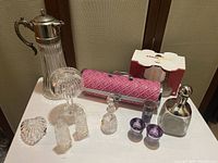 Overview of full lot: crystal decanter with silver lid and handle, crystal heart box, salt and pepper set, candle holder, ballerina figurine, pink wine purse holder, Patron shaker, shot and wine glasses
