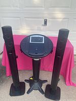 Photo of two black Philips HTS 5580 tower speakers standing upright beside the karaoke machine on a stand.