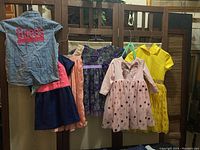 Photo showing 5 girls dresses hanging including Guess chambray shirt and various colored dresses