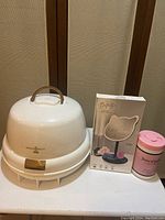 White Gold N Hot 1400 portable hair dryer with gold handle and latch, showing scratches, pictured with boxed cat-shaped vanity mirror and pink Juicy Couture hand wipes container.