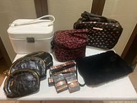 Photo showing 10 assorted makeup bags arranged in a group along with multiple e.l.f. cosmetic products such as eyeshadows, blushes, and bronzers.