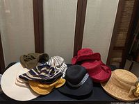Group photo of assorted ladies hats including straw and fabric types in various colors arranged on a white surface.