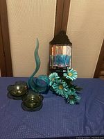 Photo showing all items including the Murano ribbon swirl blue glass sculpture, green glass bowls, artificial blue flowers, and the vintage wall sconce with mirror and candle holder.