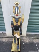 Front view of the statue showing the ram-headed figure with ornate gold headdress and staff.