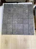 Top view of one sheet showing 36 small square dark gray mosaic tiles with stone texture.