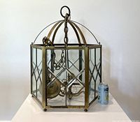 Front view of large vintage brass and glass chandelier showing geometric glass panes and brass frame with hanging chain.