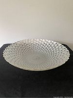 Top view angle of etched glass bowl placed on black cloth, showing the full pattern and scalloped rim.