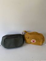 Photo of green and mustard yellow fanny packs side by side against a white background