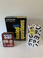 Photo of three boxed/card games: Loaded Questions, Cards Against Humanity Family Edition, Sushi Go! tin