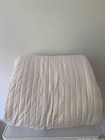Folded view of the beige cotton velvet bed cover showing channeled quilting pattern and texture.