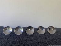 Front view of 5 round concave chrome knobs showing their reflective curved surfaces.