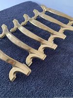 Close-up shot of five brass plated cabinet pulls showing detailed shape and finish.