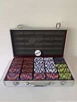 Open aluminum case showing the poker chip set with multiple color chips and dealer chip inside foam cushion.