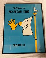 Framed festival poster showing colorful graphic art with text 'Festival Du Nouveau Rire Trouville'