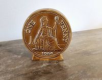 Front view of the ceramic bank shaped as a large 1964 British one penny coin depicting Britannia