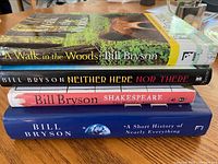 Four stacked hardcover books by Bill Bryson showing spine titles and author name.