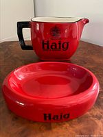 Front view of red ceramic water jug and matching ashtray with Haig Scotch Whiskey logos