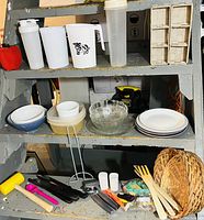 Overview of assorted kitchenware items displayed on an industrial step ladder includes pitchers, bowls, plates, utensils, baskets, and small tools.