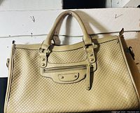 Front view of beige Danier purse showing woven leather texture, two handles, and front zippered pocket