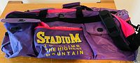 Side view of purple and pink duffel bag with yellow and white text on side pocket.