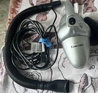 Euro-Pro handheld vacuum cleaner with black flexible hose and power cord shown on patterned cloth surface.
