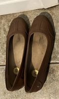 Pair of size 8 brown ladies flat shoes on a tiled floor, showing top view.