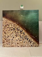 Front-facing photo of the square beach scene canvas art showing the sandy crowded shore and adjacent ocean