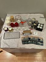 Full view of all candles, holders, and accessories arranged on a cloth showing variety of items in the lot