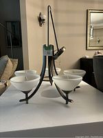 Chandelier on table showing metal frame and frosted glass shades before installation.