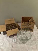 Photo of clear crystal punch bowl and 12 cups in separated cardboard boxes on a white surface