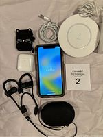 All accessories and phone arranged on surface showing front of iPhone with 'hello' screen greeting