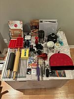 Overview of kitchen items showing variety of baking and cooking tools, Le Creuset saucepan, recipe binder, Cuisinart grinder, rolling pins, and measuring devices.