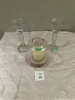 Photo showing all three candle holders together on white cloth backdrop, numbered lot tag visible.