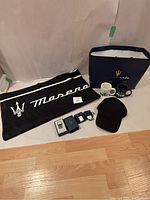 Full lot laid out showing all items included: beach towel, keychain, cufflinks, hat, two mugs, and branded shopping bag.