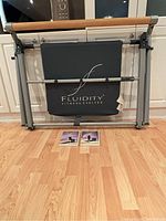 Folded Fluidity Barre system with branding and 2 DVDs on floor.