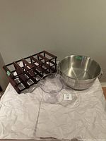 Wooden wine rack, acrylic ice bucket, and stainless steel beer bucket on a white cloth.