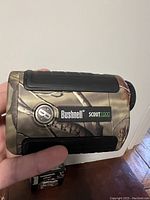 Rangefinder held in hand showing front body with Bushnell logo and Scout 1000 marking