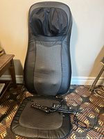 Full view of the Dr. Ho's 3D Shiatsu Massage Cushion showing backrest and seat section with the remote control resting on the seat.