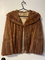 Front view of short brown mink fur jacket on hanger