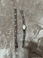 Full view of the Gruen 11 quartz watch next to a matching metal mesh bracelet on a soft gray fabric background.