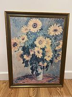 Front facing view of the large framed sunflower painting showing the bouquet with multiple yellow flowers in a vase on a blue and pinkish background.