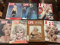 Eight vintage LIFE magazines with Marilyn Monroe on the covers laid out on a table showing various covers and dates